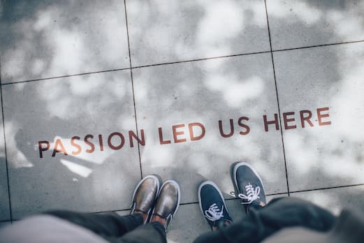 Two people standing on a sign that says passion led us here